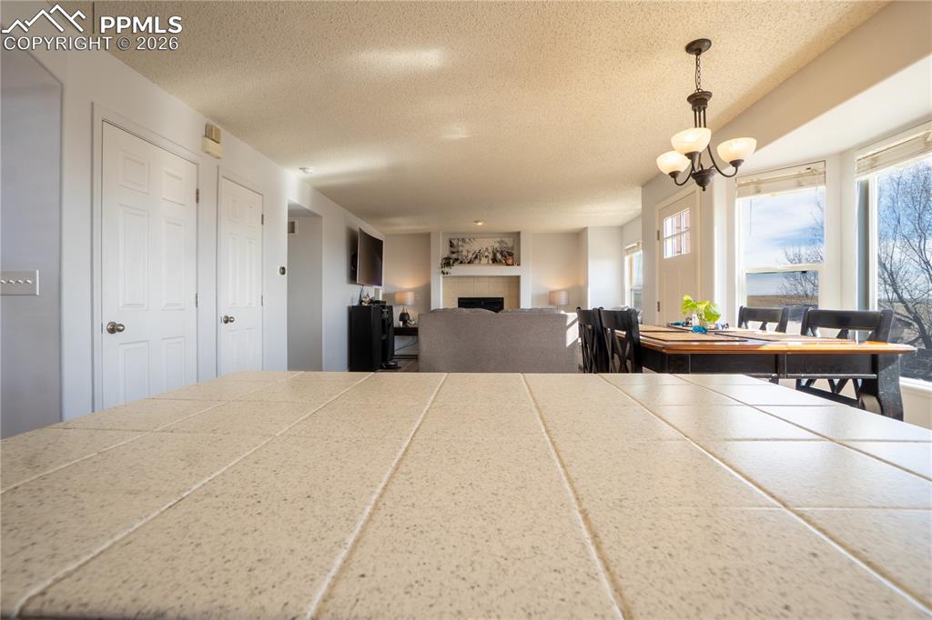 Image 10 of 40: Dining space with a fireplace, a textured ceiling, and suspended lighting