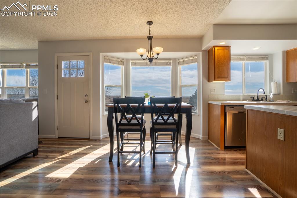 Image 11 of 40: Dining space with dark wood-type flooring, hanging lights, and a textured c
