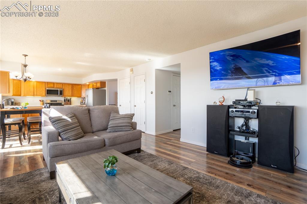Image 13 of 40: Living room with dark wood-type flooring, a chandelier, and a textured ceil