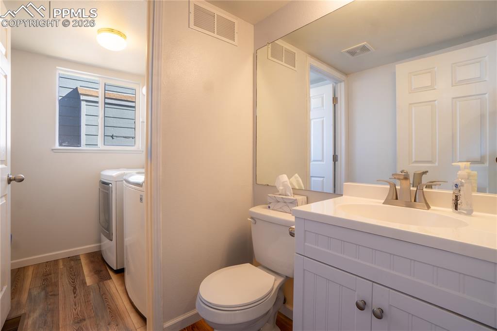 Image 14 of 40: Bathroom with vanity, washer and clothes dryer, and dark wood-style floorin