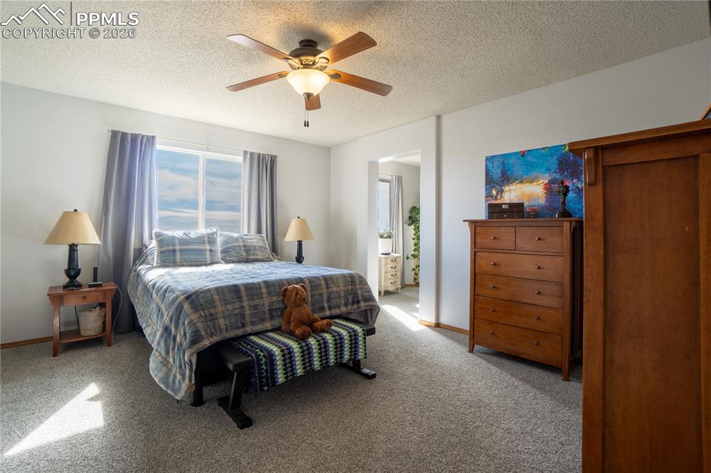 Image 16 of 40: Bedroom featuring carpet, a textured ceiling, ceiling fan, and ensuite bath