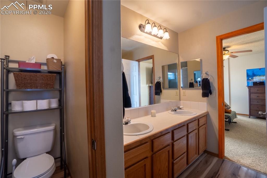 Image 21 of 40: Bathroom with double vanity, dark wood-style flooring, and a ceiling fan