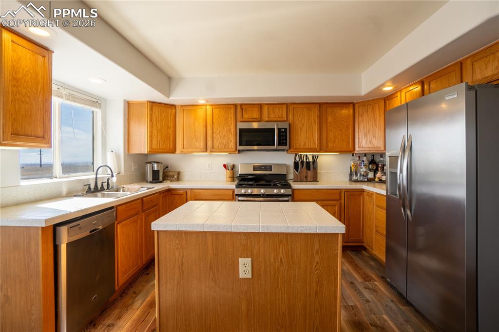 Image 7 of 40: Kitchen featuring stainless steel appliances, a center island, wood finish