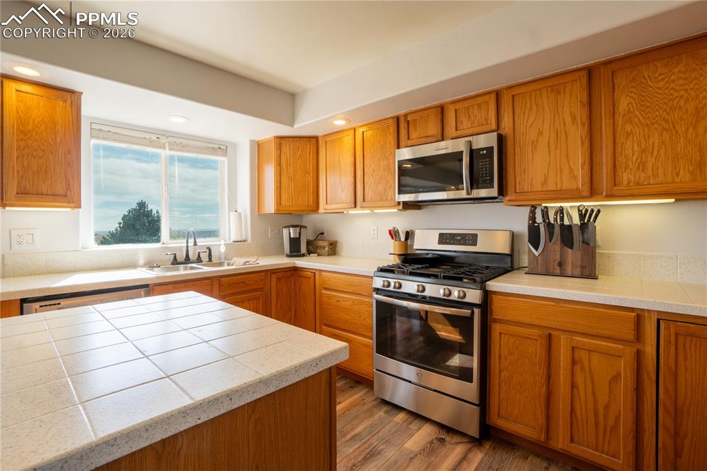 Image 8 of 40: Kitchen with stainless steel appliances, wood finish cabinets, dark wood-st