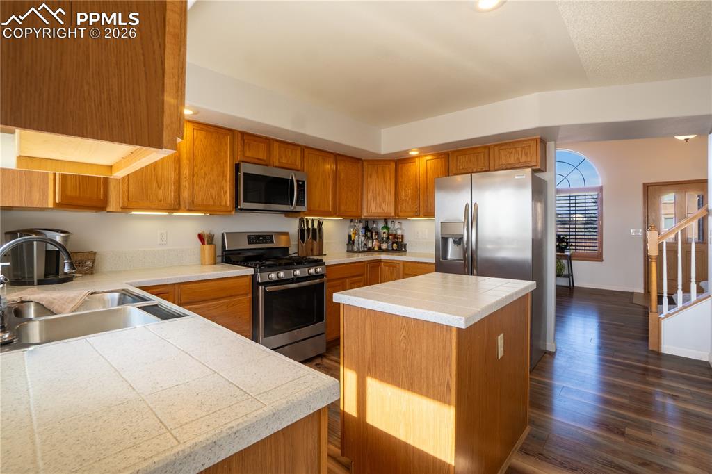 Image 9 of 40: Kitchen featuring stainless steel appliances, wood finish cabinets, tile co