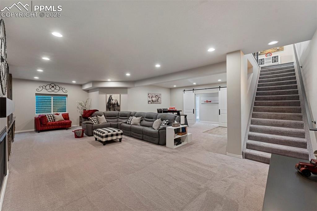 Image 35 of 49: Living room featuring a barn door, stairs, recessed lighting, and light col