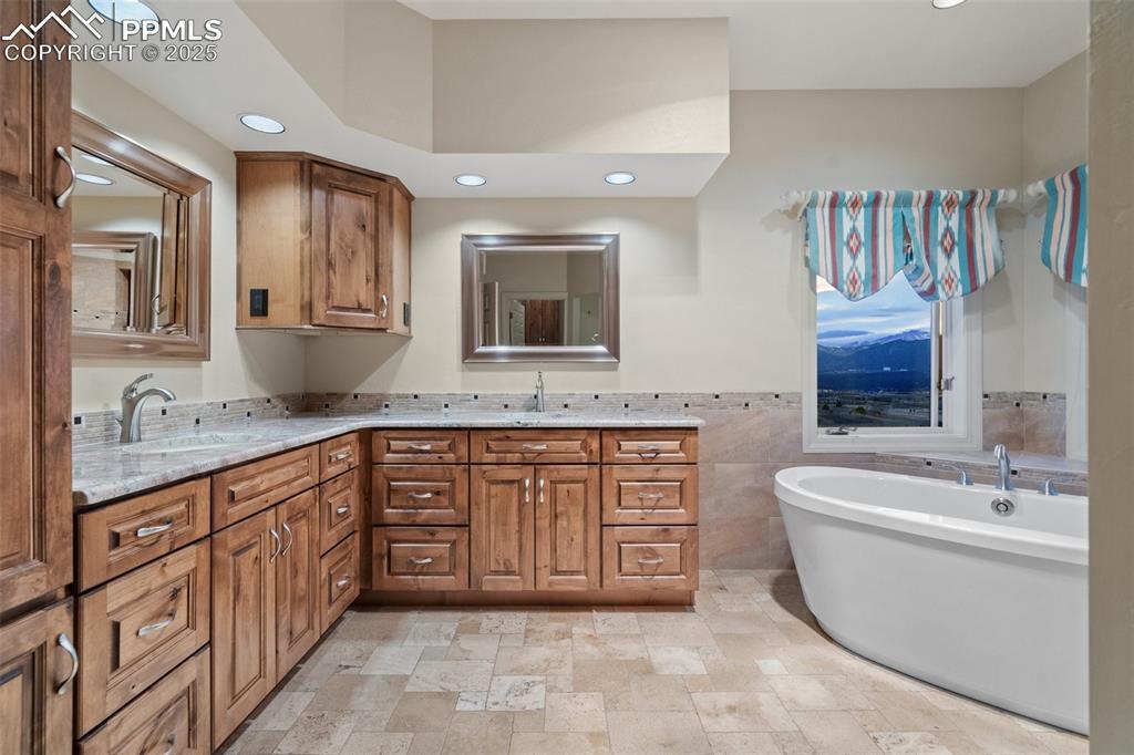 Image 32 of 48: Full bath featuring tile walls, stone finish flooring, double vanity, a fre