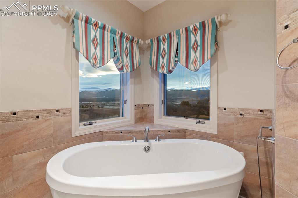Image 33 of 48: Bathroom with tile walls, a mountain view, and a soaking tub