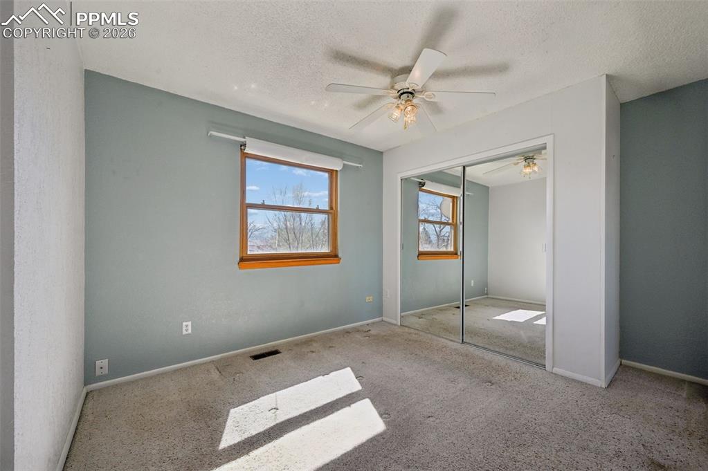 Image 11 of 25: Unfurnished bedroom with a ceiling fan, carpet, a textured ceiling, and a c