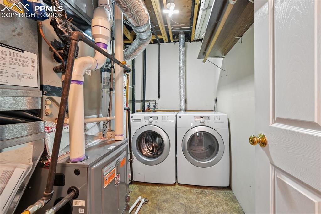 Image 15 of 25: Laundry area with heating unit, unfinished concrete floors, and washer and
