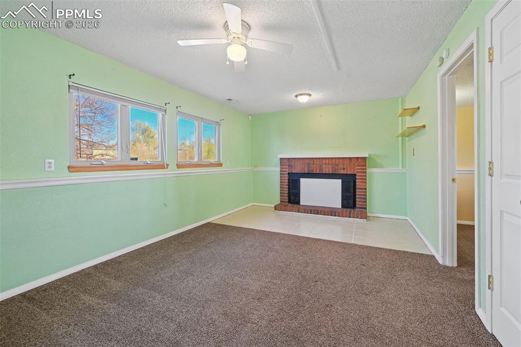 Image 16 of 25: Unfurnished living room featuring ceiling fan, a textured ceiling, light ca
