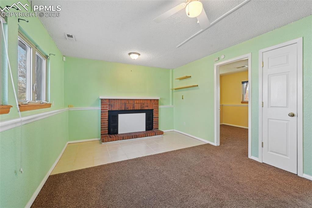 Image 17 of 25: Unfurnished living room featuring light carpet, a brick fireplace, a textur