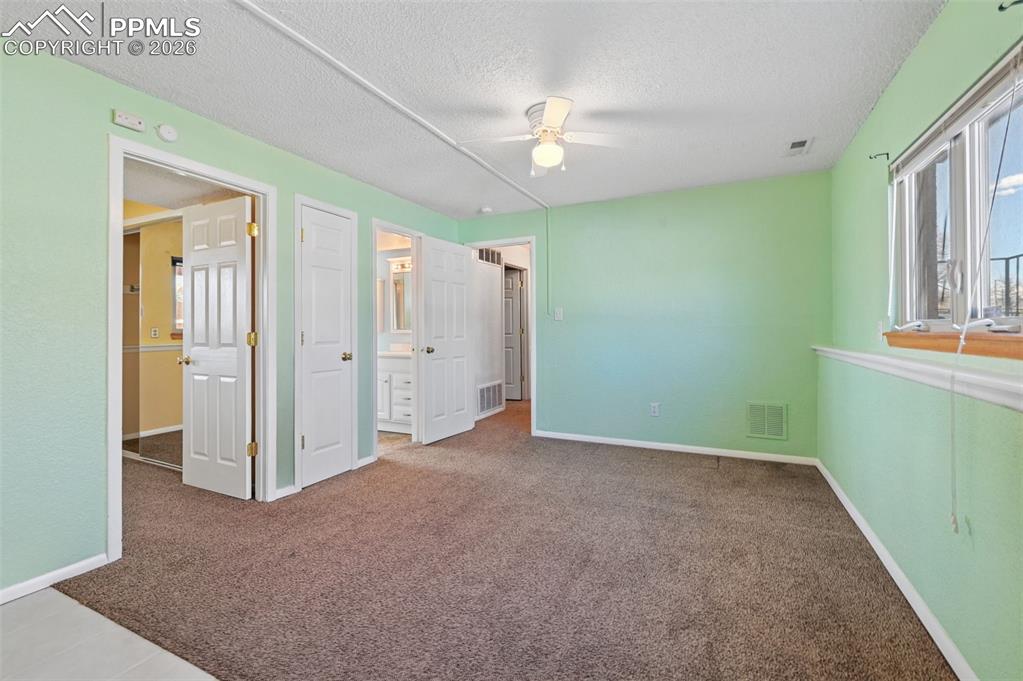 Image 18 of 25: Unfurnished bedroom with carpet flooring, a textured ceiling, connected bat