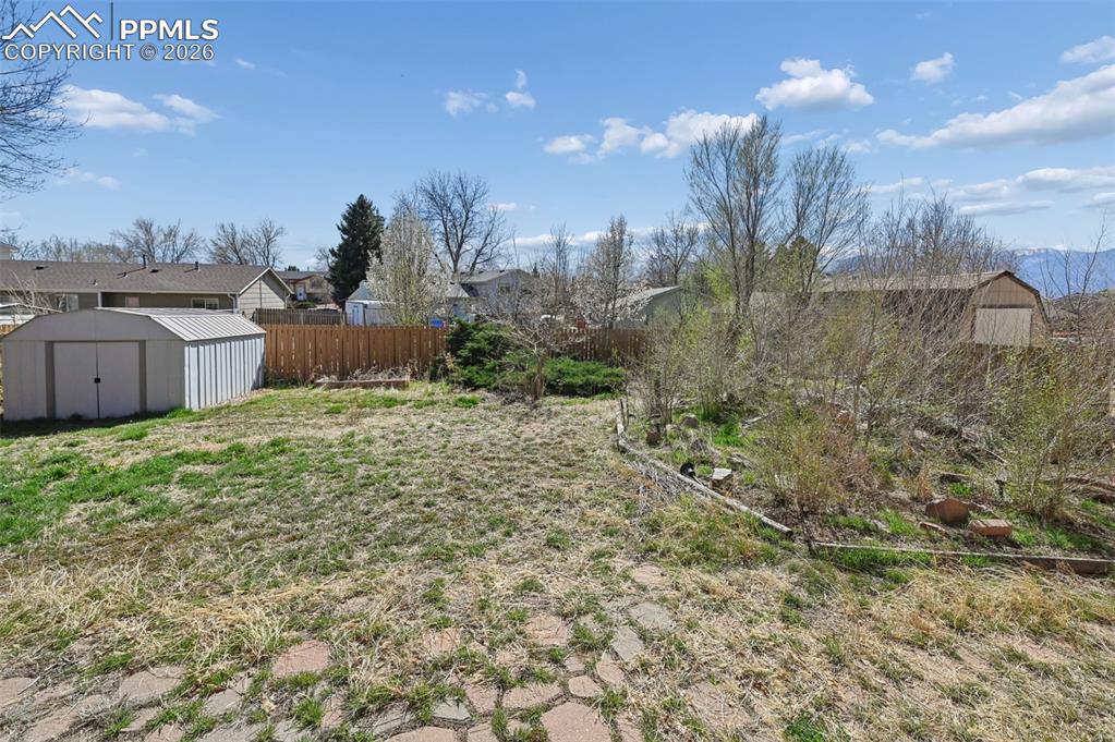 Image 23 of 25: Fenced yard featuring a shed and a residential view