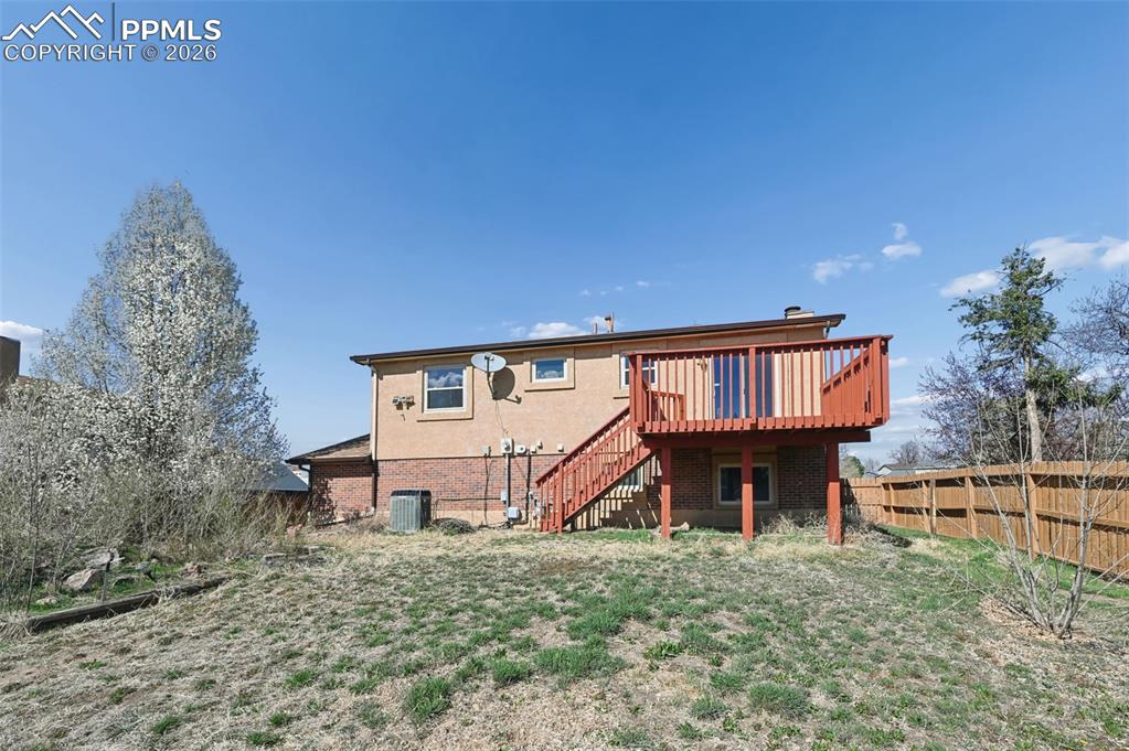 Image 25 of 25: Rear view of property featuring a fenced backyard, a deck, and brick siding