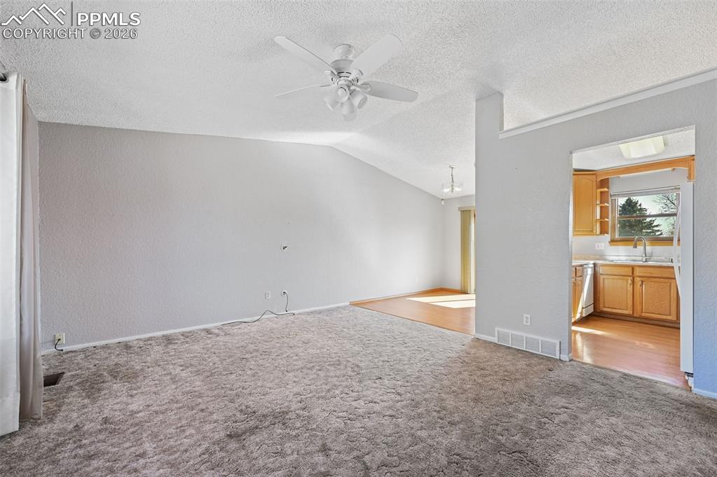 Image 4 of 25: Unfurnished living room with a ceiling fan and light carpet