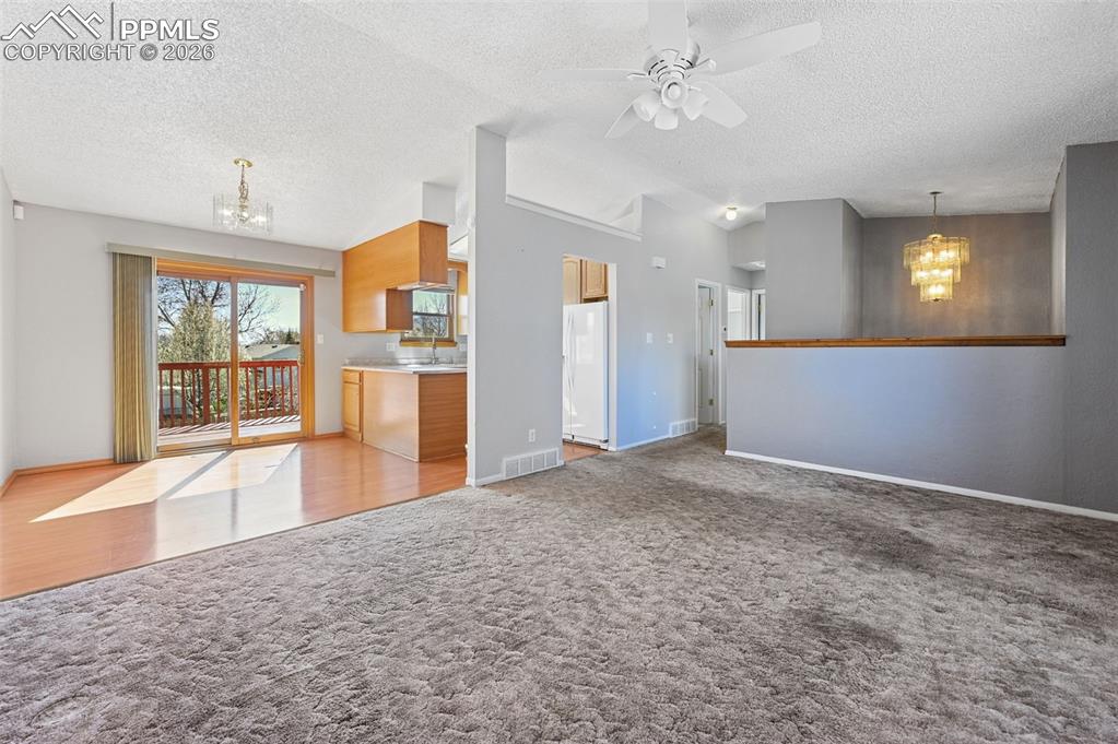 Image 5 of 25: Unfurnished living room with a chandelier, ceiling fan, and light colored c