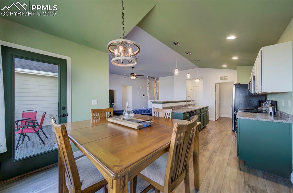 Image 13 of 45: Dining room with walk-out to back deck, luxury vinyl flooring, and chandeli