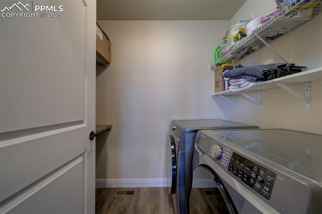 Image 17 of 45: Laundry room with shelving above washer and dryer and shelving across.