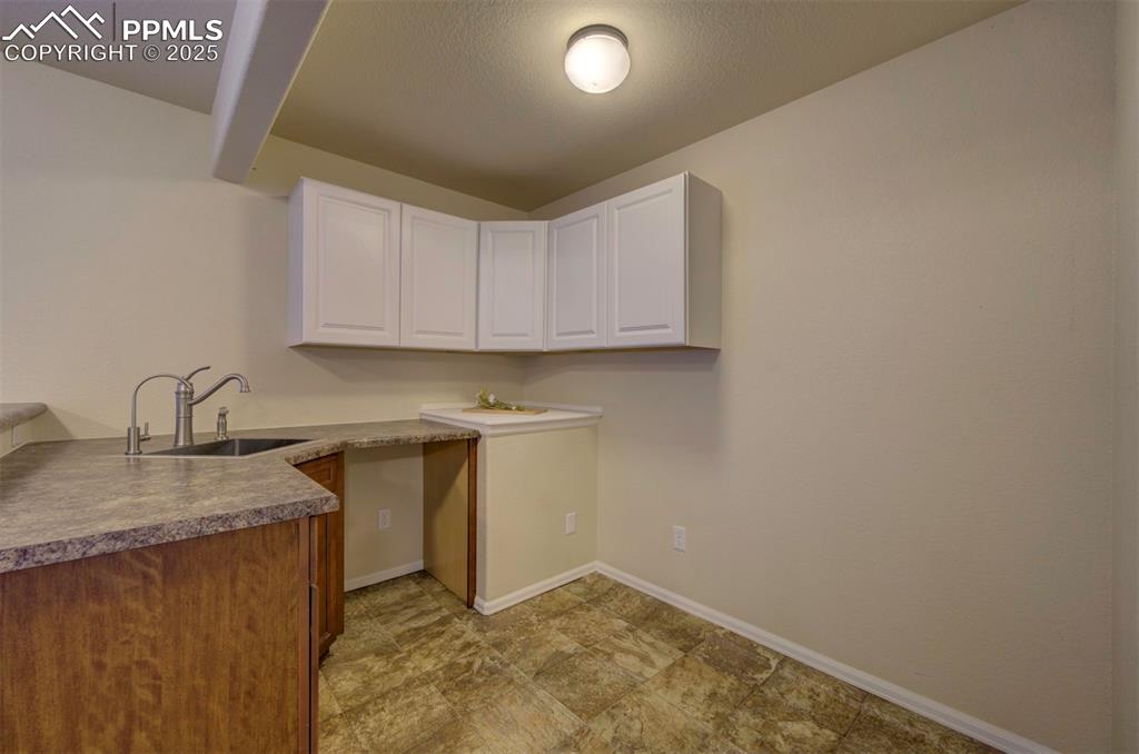 Image 30 of 45: Kitchnette/wet bar with sink, cabinet space, and room for fridge.