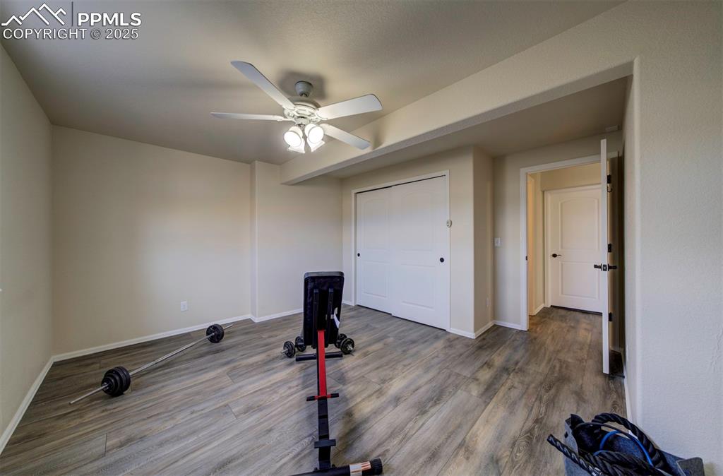 Image 33 of 45: Bedroom in basement currently used as a work out room, closet, ceiling fan,