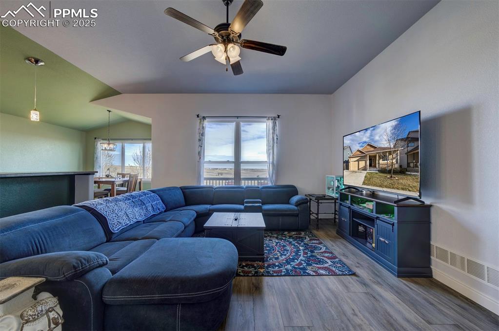 Image 5 of 45: Living area with luxury vinyl floors, lofted ceiling, and ceiling fan
