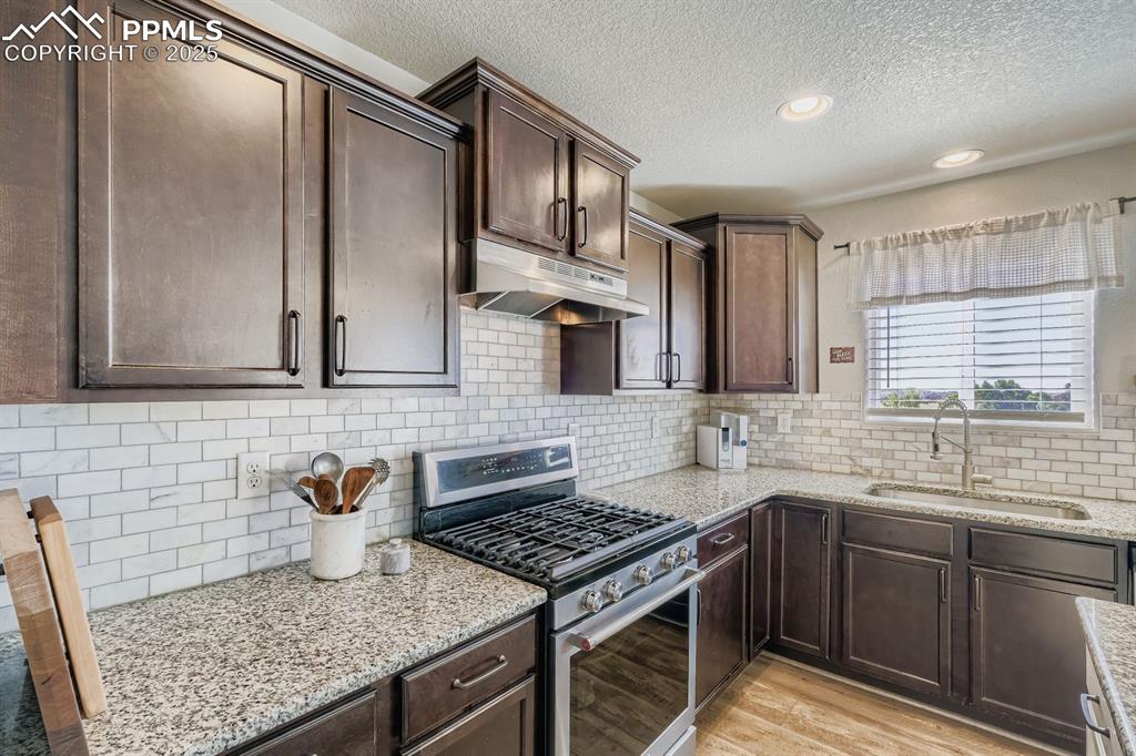 Image 9 of 42: Gorgeous granite and backsplash. Gas burner range/oven. Window over the k