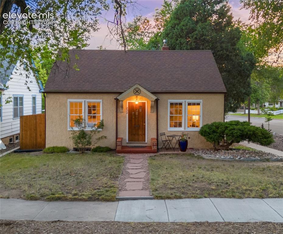 Caption: Warm stucco exterior with a brown shingle roof