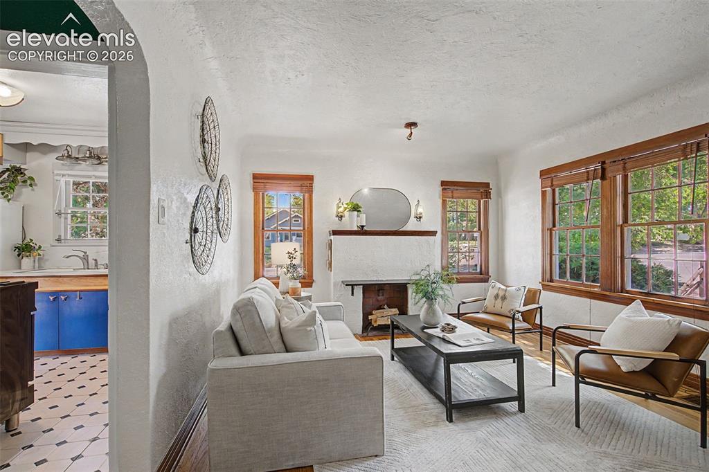 Image 11 of 37: Living area featuring a textured white wall finish, a built-in fireplace wi
