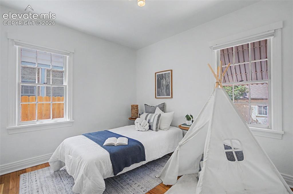 Image 19 of 37: Bright room featuring two large windows with white trim, wood-finish floori