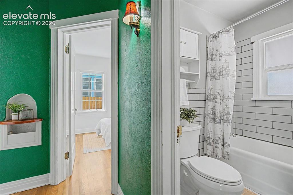 Image 21 of 37: Bathroom featuring subway tile surround, a built-in tub, and a white toilet