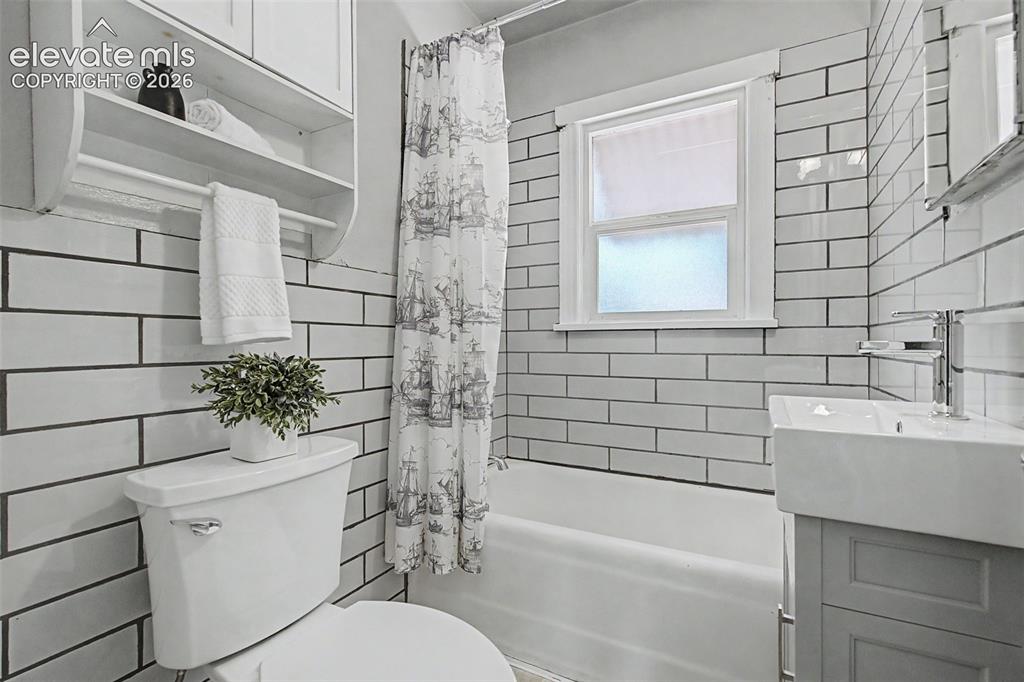 Image 22 of 37: Bathroom featuring white subway tile walls with dark grout, a white bathtub