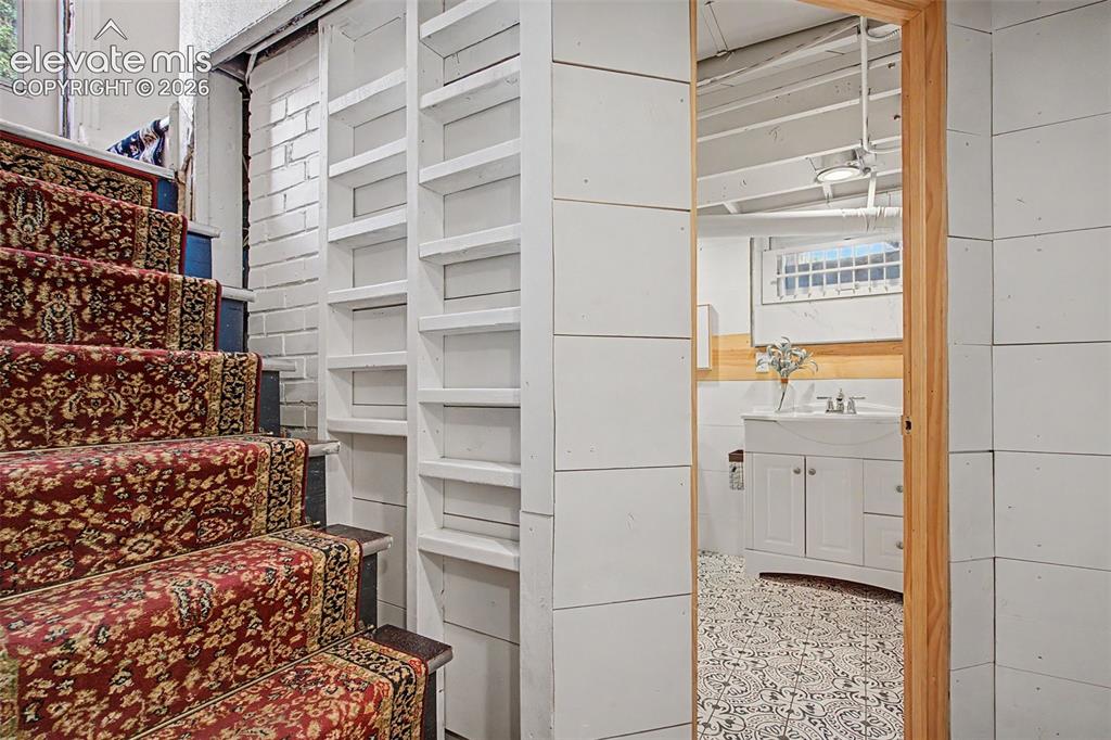Image 25 of 37: Staircase with patterned runner, white painted brick wall, built-in shelvin