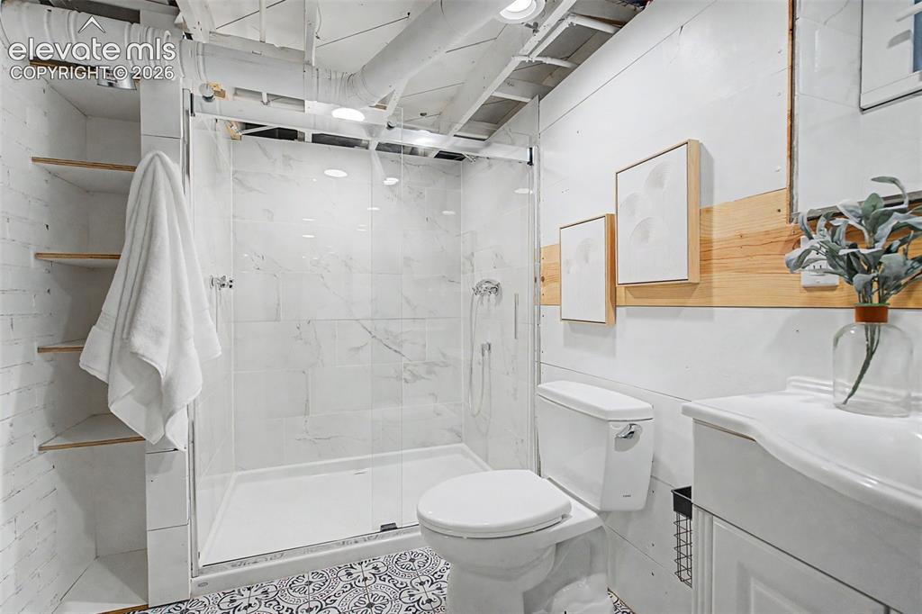 Image 26 of 37: Bathroom featuring a glass-enclosed shower with white tiled walls, a white