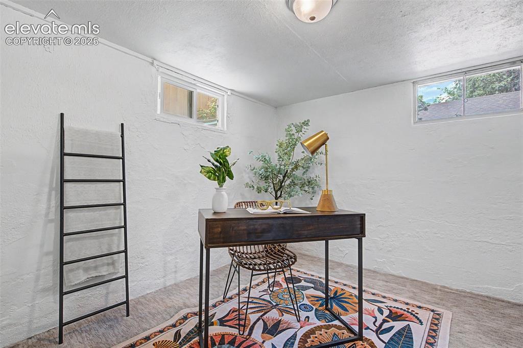 Image 27 of 37: White painted walls, wood-finish flooring, two upper windows, and a flush m