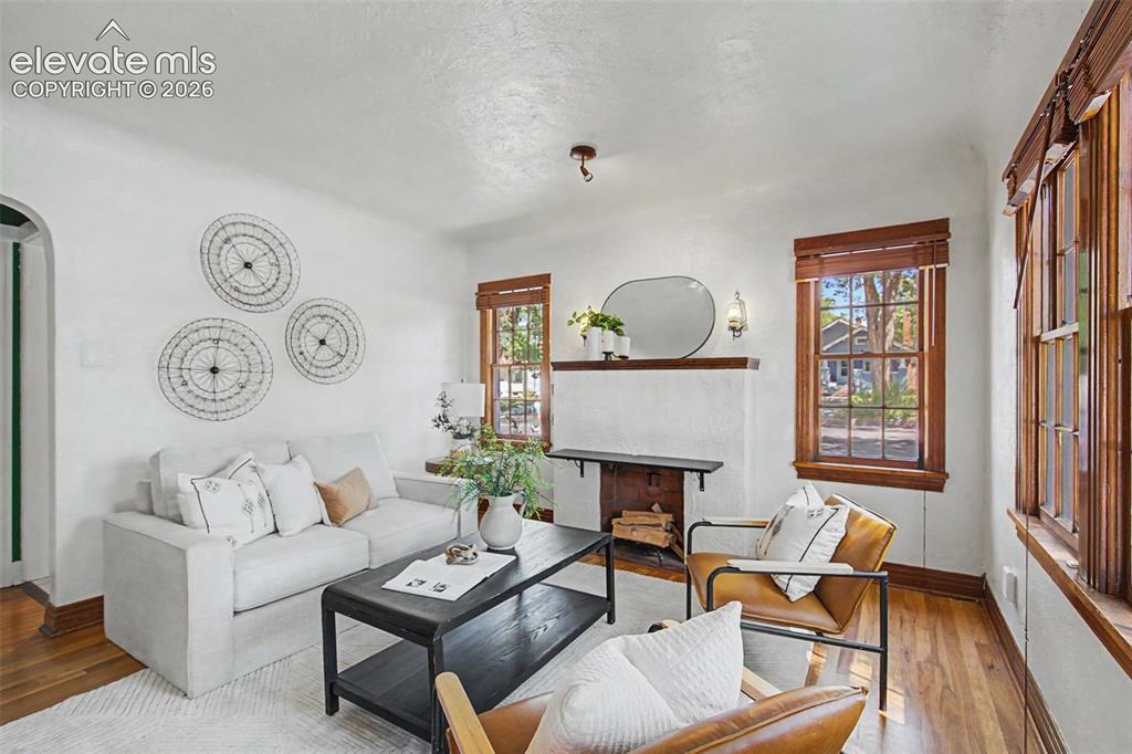 Image 6 of 37: Living area featuring wood-finish flooring, white walls, and a fireplace wi
