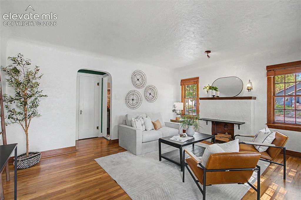 Image 7 of 37: Living area featuring wood-finish flooring, white painted walls, and an arc