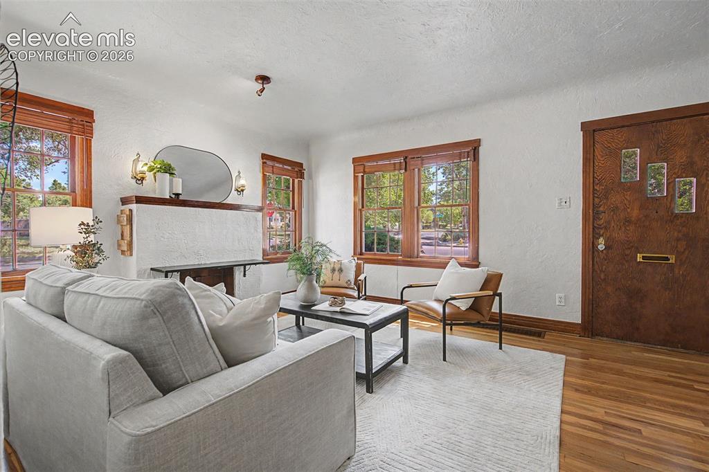 Image 9 of 37: Living room featuring hardwood flooring and a textured white fireplace with