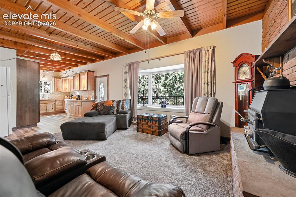 Image 11 of 50: Exposed wood beam ceiling, bay window, wood-burning stove with brick surrou