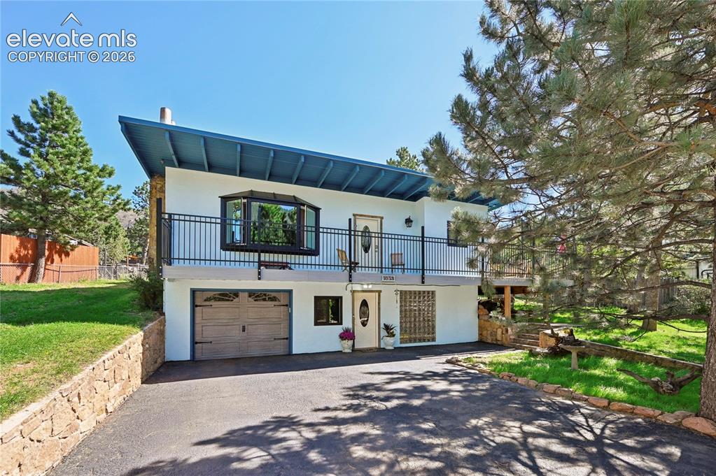 Image 2 of 50: Stucco exterior with a blue overhanging roof, featuring a bay window and a 
