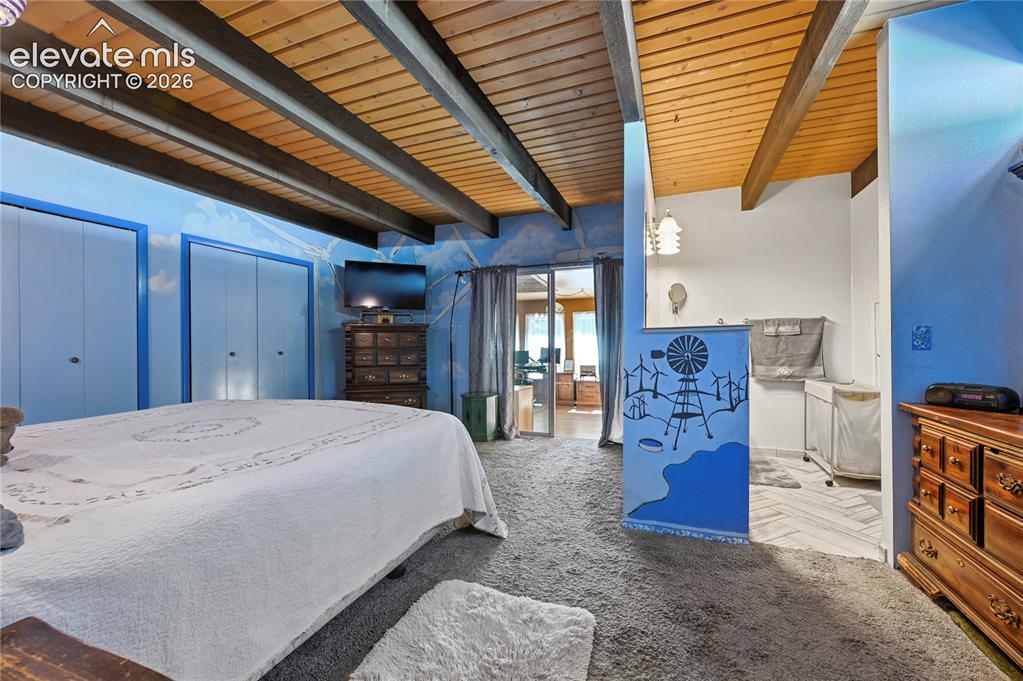Image 25 of 50: Main Bedroom, Exposed beam ceiling with wood paneling, sliding closet doors