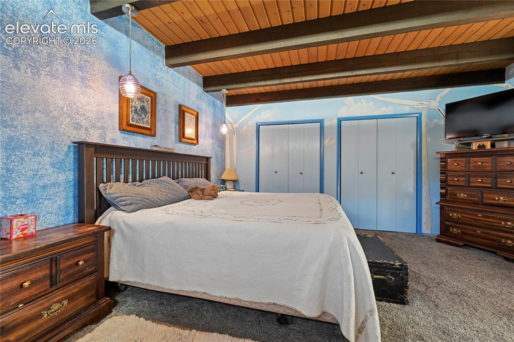 Image 26 of 50: Main Bedroom, Vaulted wood-paneled ceiling with exposed beams, textured blu