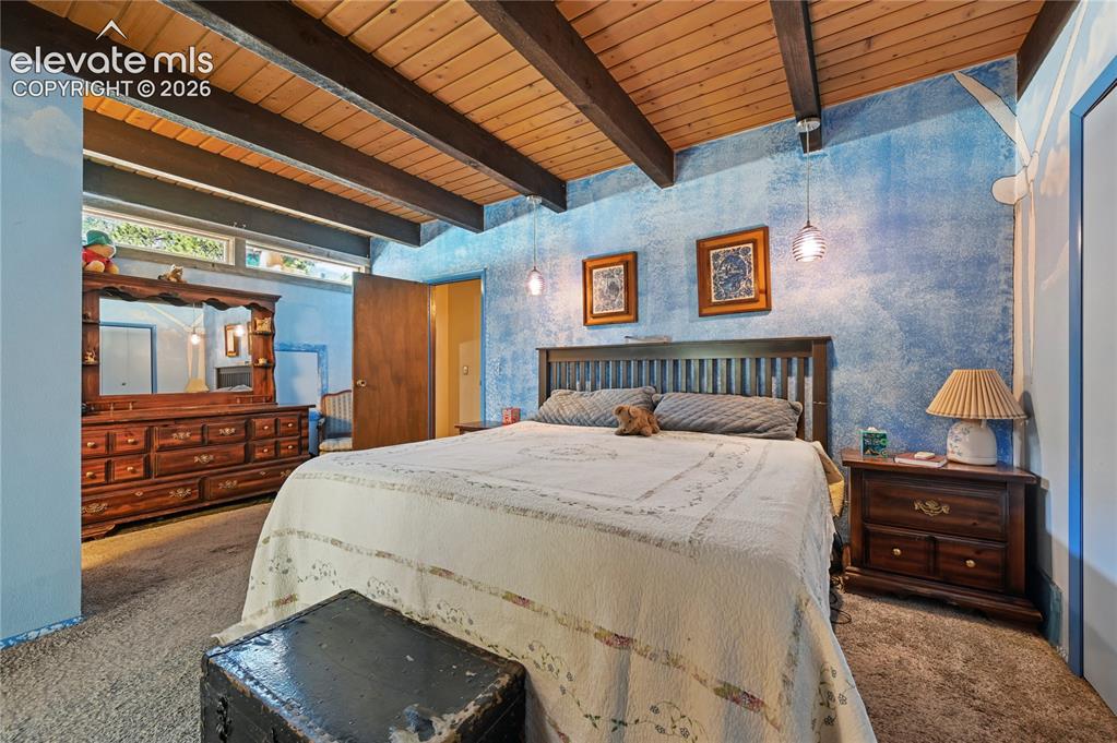 Image 27 of 50: Main Bedroom, Exposed wood beam ceiling, blue textured wall finish, wood-fi