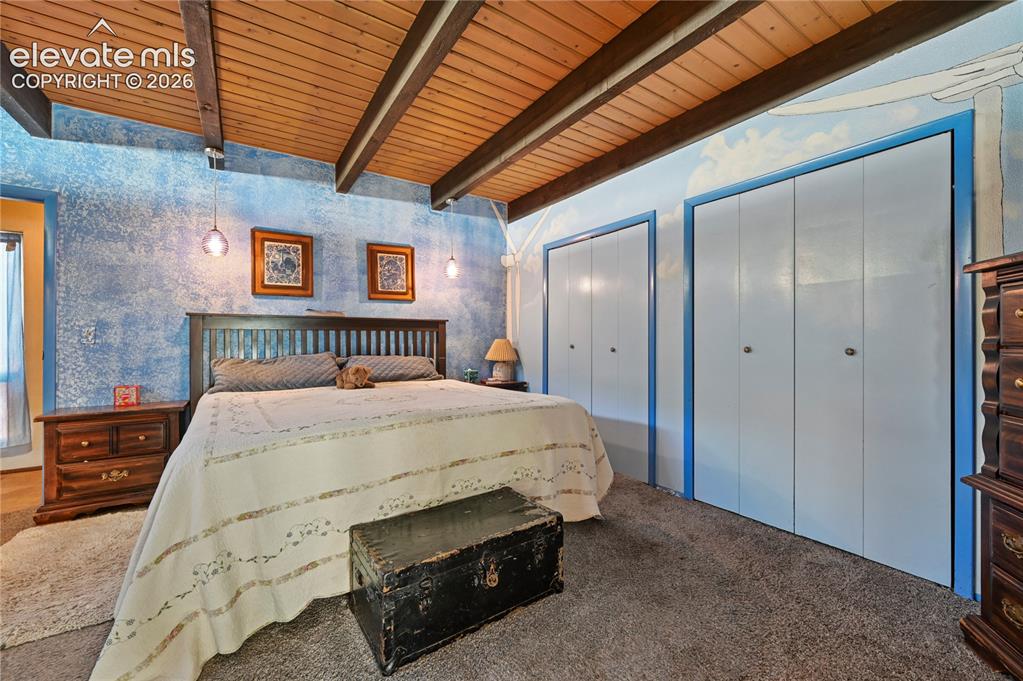 Image 28 of 50: Main bedroom, Vaulted wood-paneled ceiling with exposed beams, textured acc