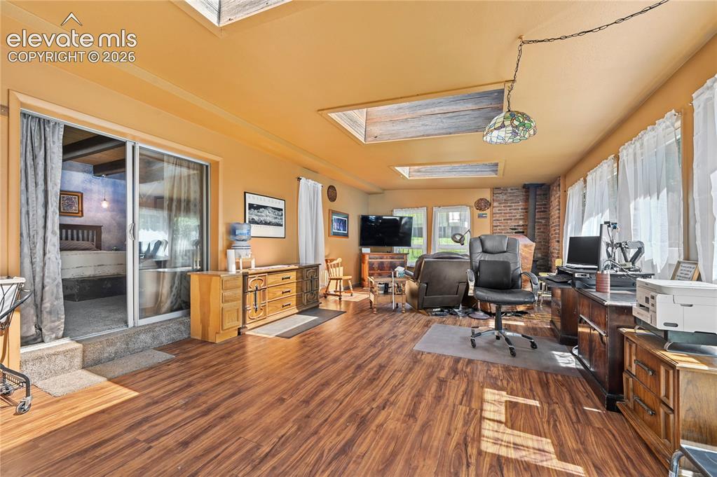 Image 34 of 50: Wood-finish flooring, multiple skylights, brick chimney feature, and a slid