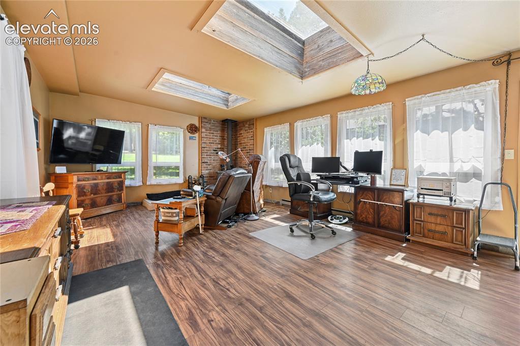Image 35 of 50: Wood-finish flooring, multiple skylights, and a brick accent wall complemen
