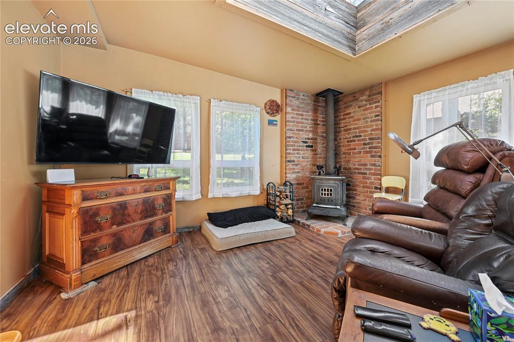 Image 37 of 50: Wood-finish flooring, exposed brick accent wall, and a skylight feature