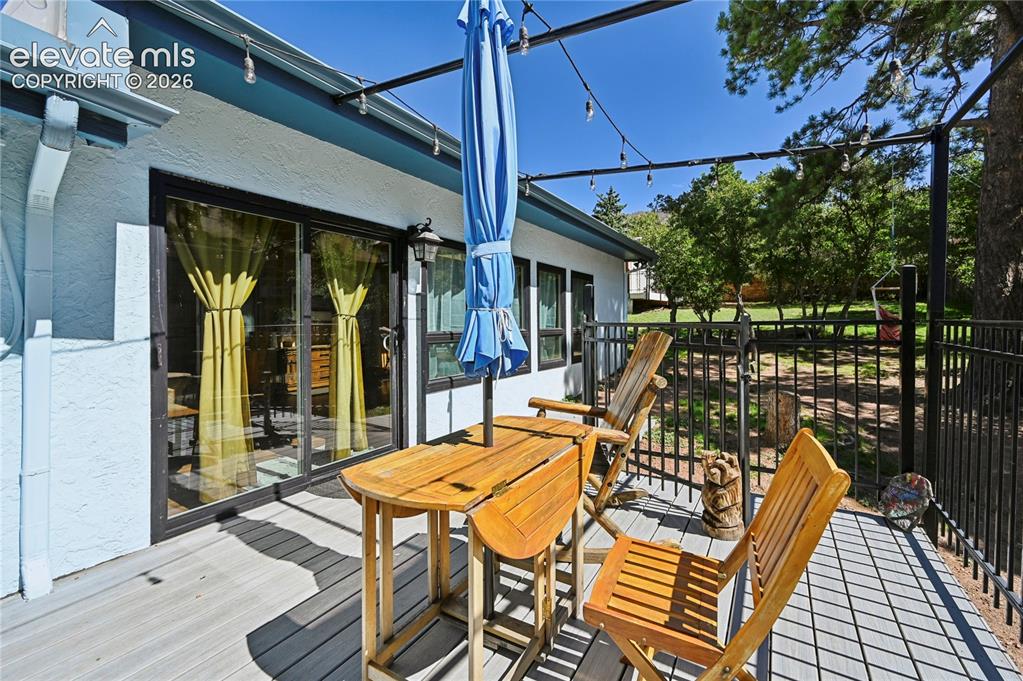 Image 42 of 50: Deck with composite decking, black metal railing, and string lighting