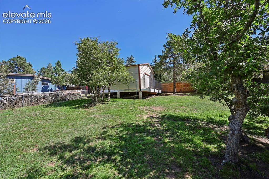 Image 44 of 50: Expansive grassy yard with mature trees and a detached structure featuring 