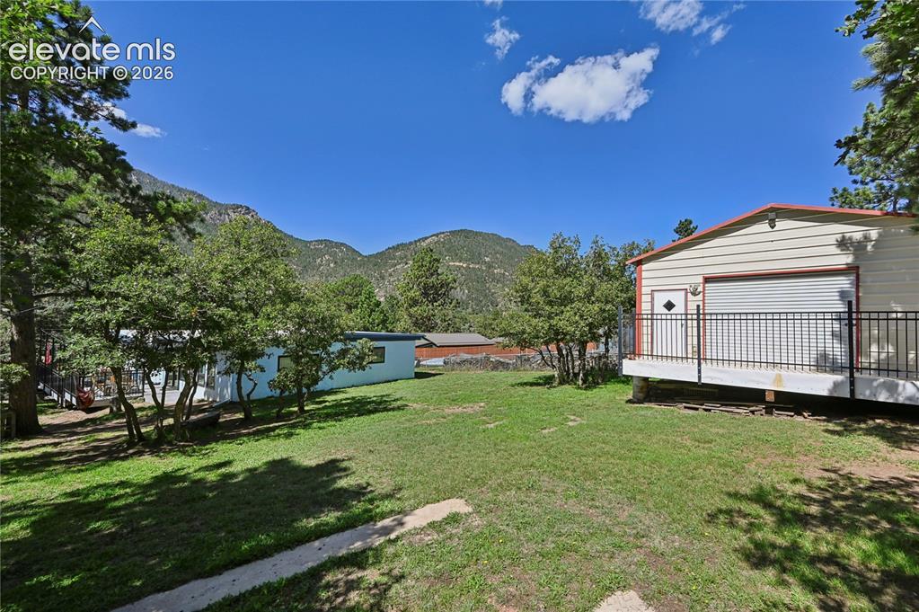 Image 46 of 50: Expansive grassy yard with mature trees, a detached auxiliary structure fea